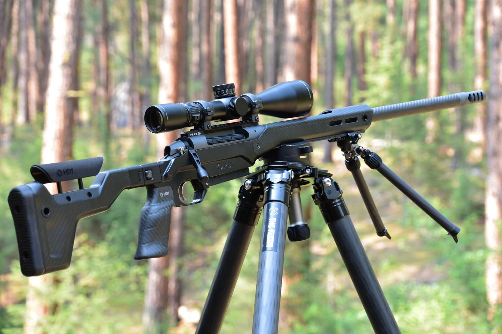 Carbon fiber Model 307 rifle is secured on a tripod in the forest.