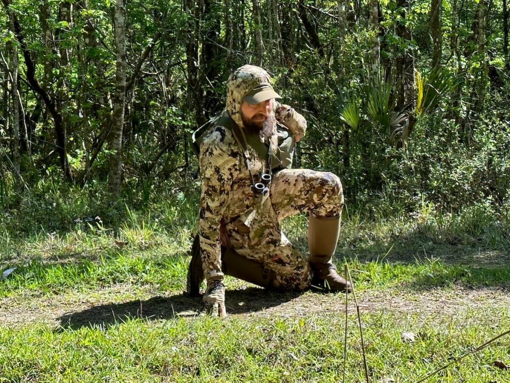 Hunter crouched low to the ground decked out in his Sitka Equinox Guard Line 