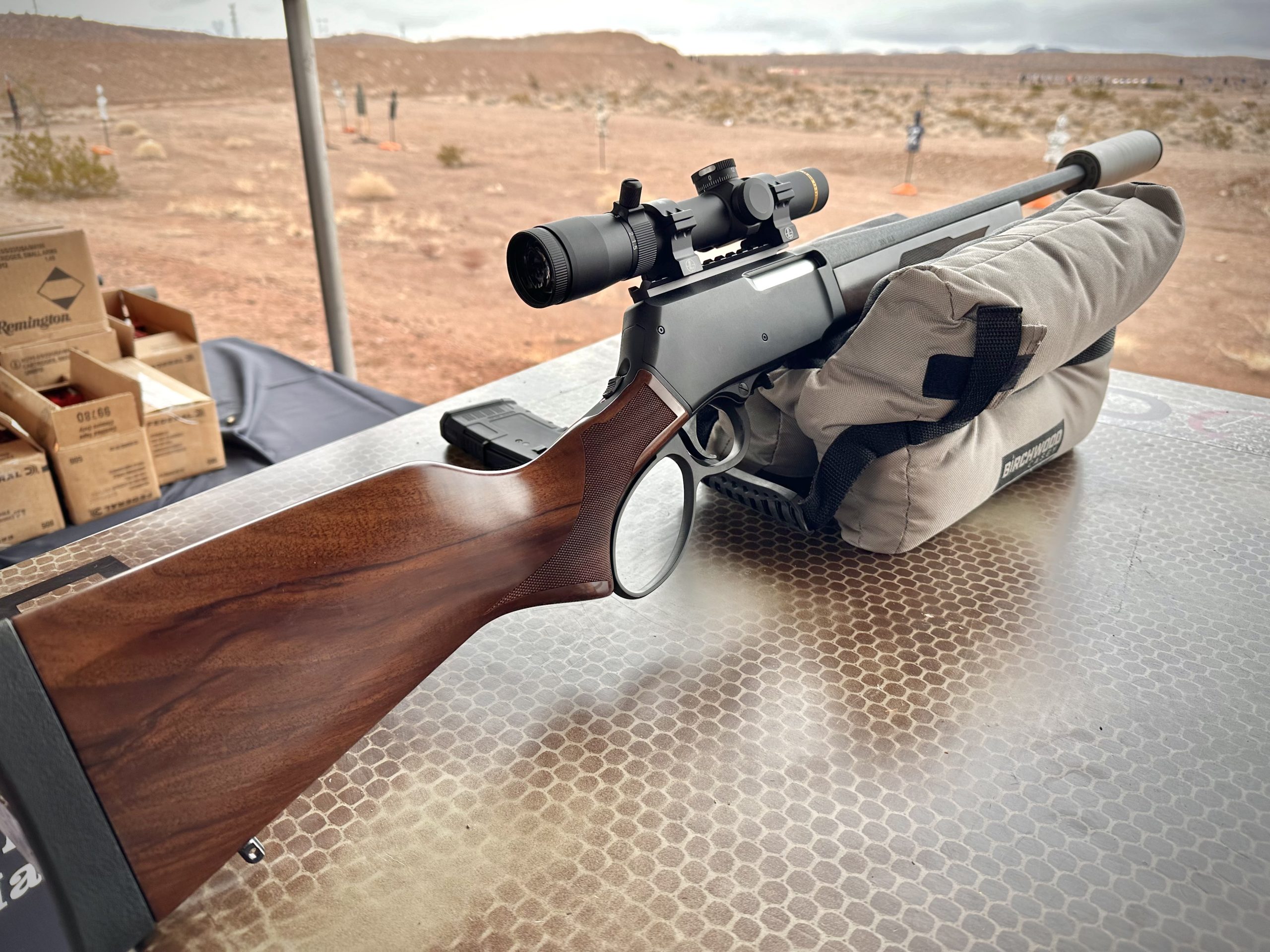 A lever action rifle rests on the shooting bench.