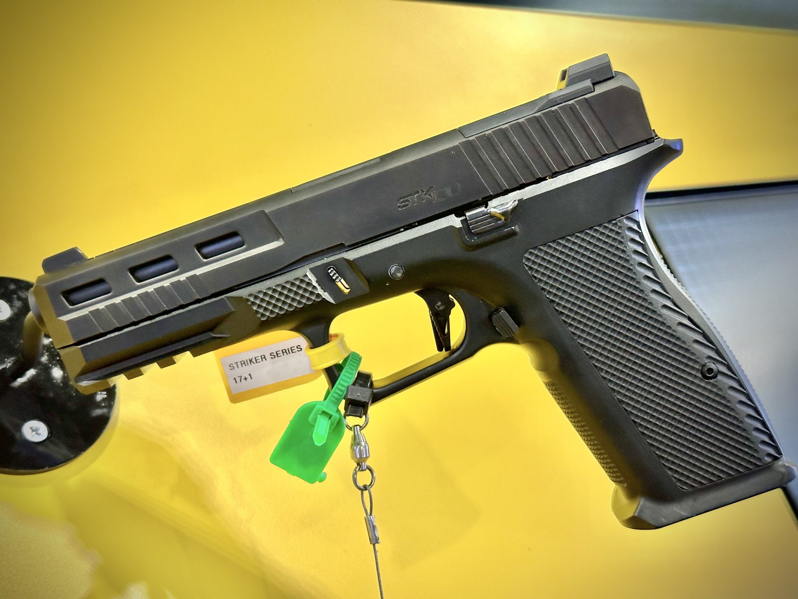 A black handgun is staged against a yellow background.