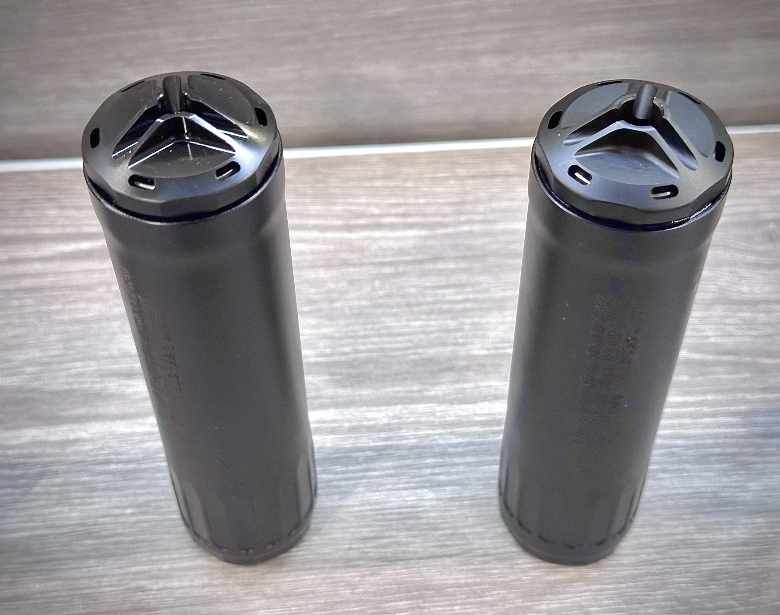 Two suppressors are displayed in a glass cabinet.