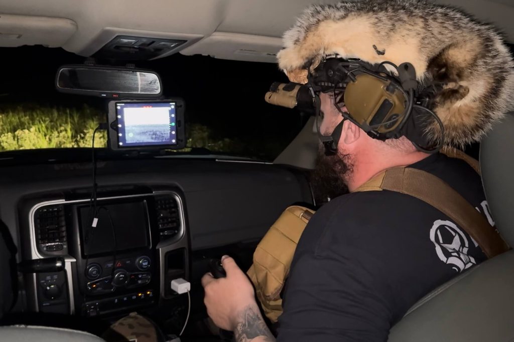 Man in truck with fur hat looking at screen showing readout from InfiRay Outdoor M6T