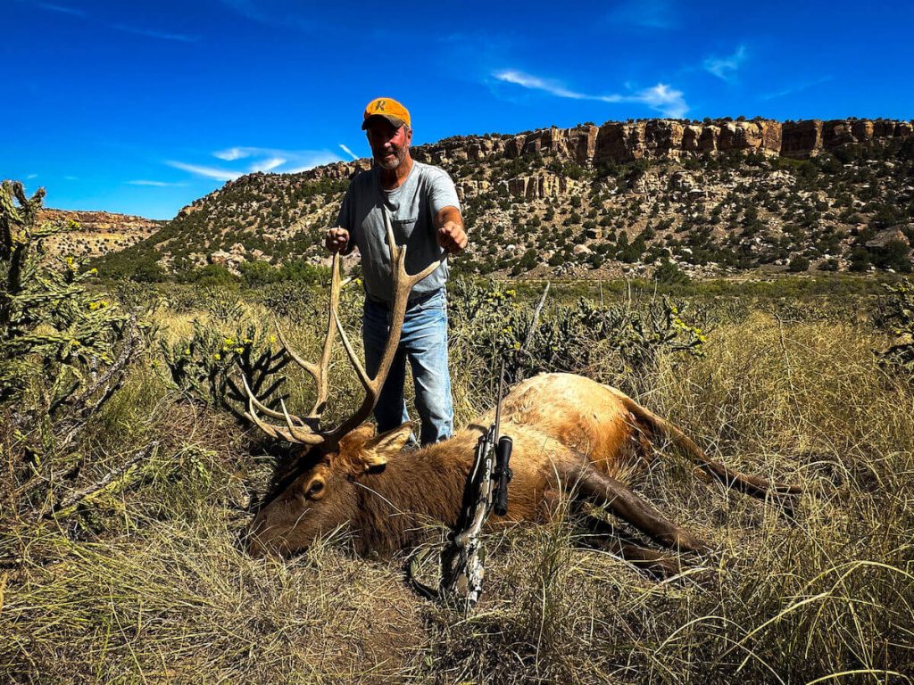 Hunter with elk and rifle in tall grass