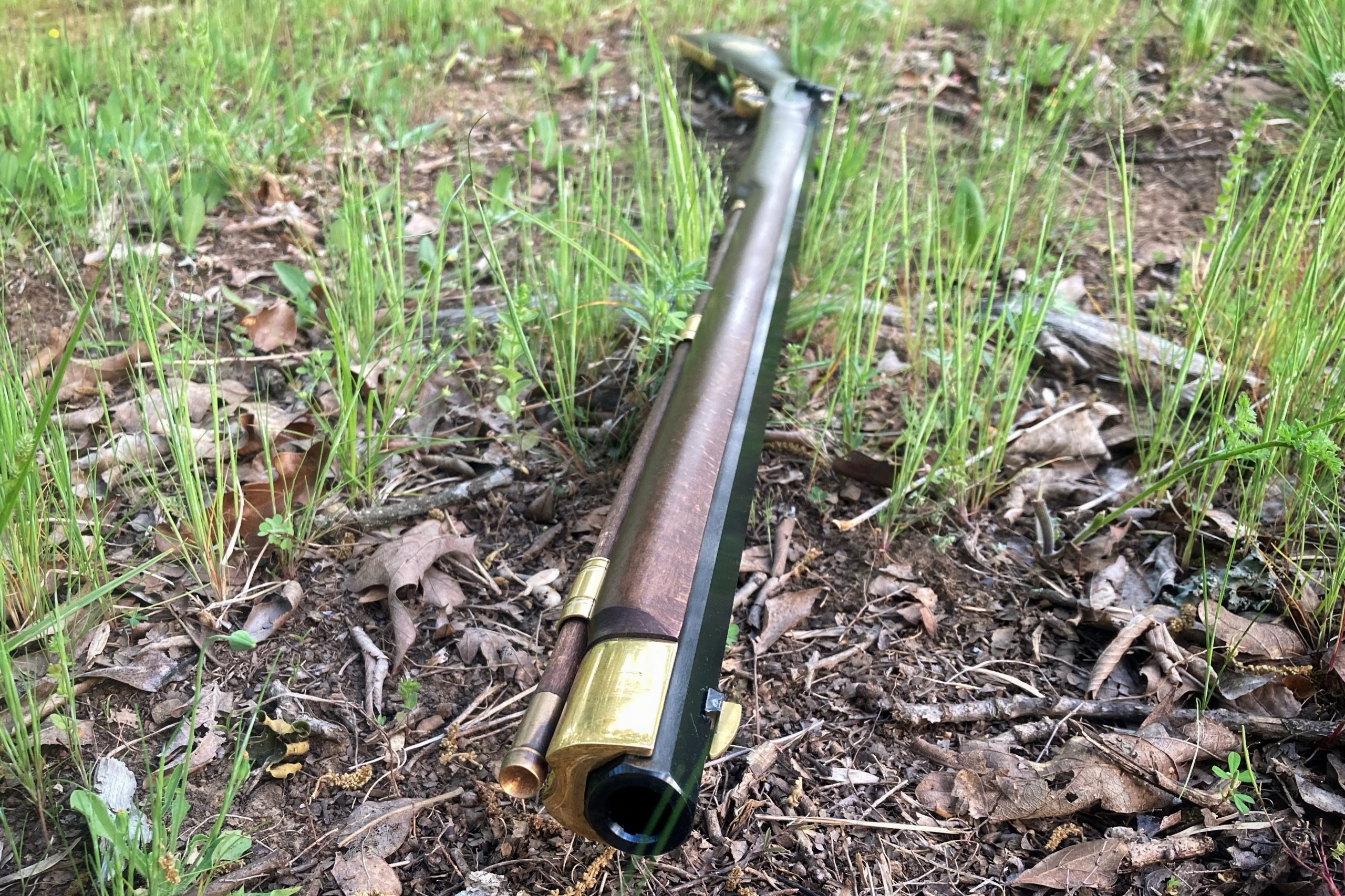 Rifle muzzle laying on ground with grass