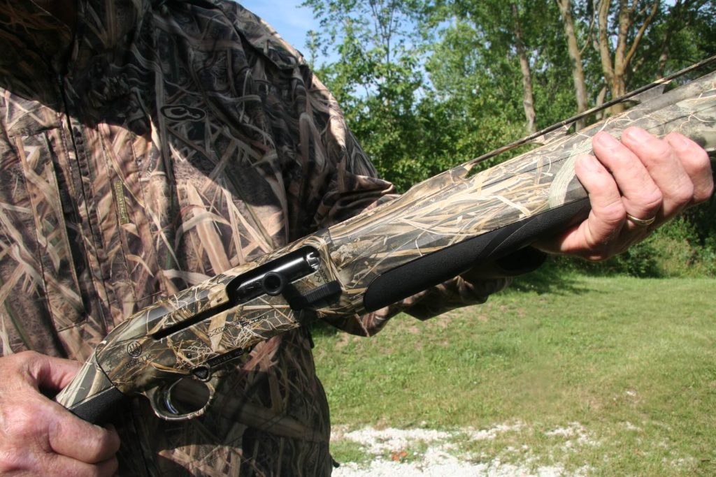 Hunter holding the Beretta A-400 and giving a close-up on the charging handle