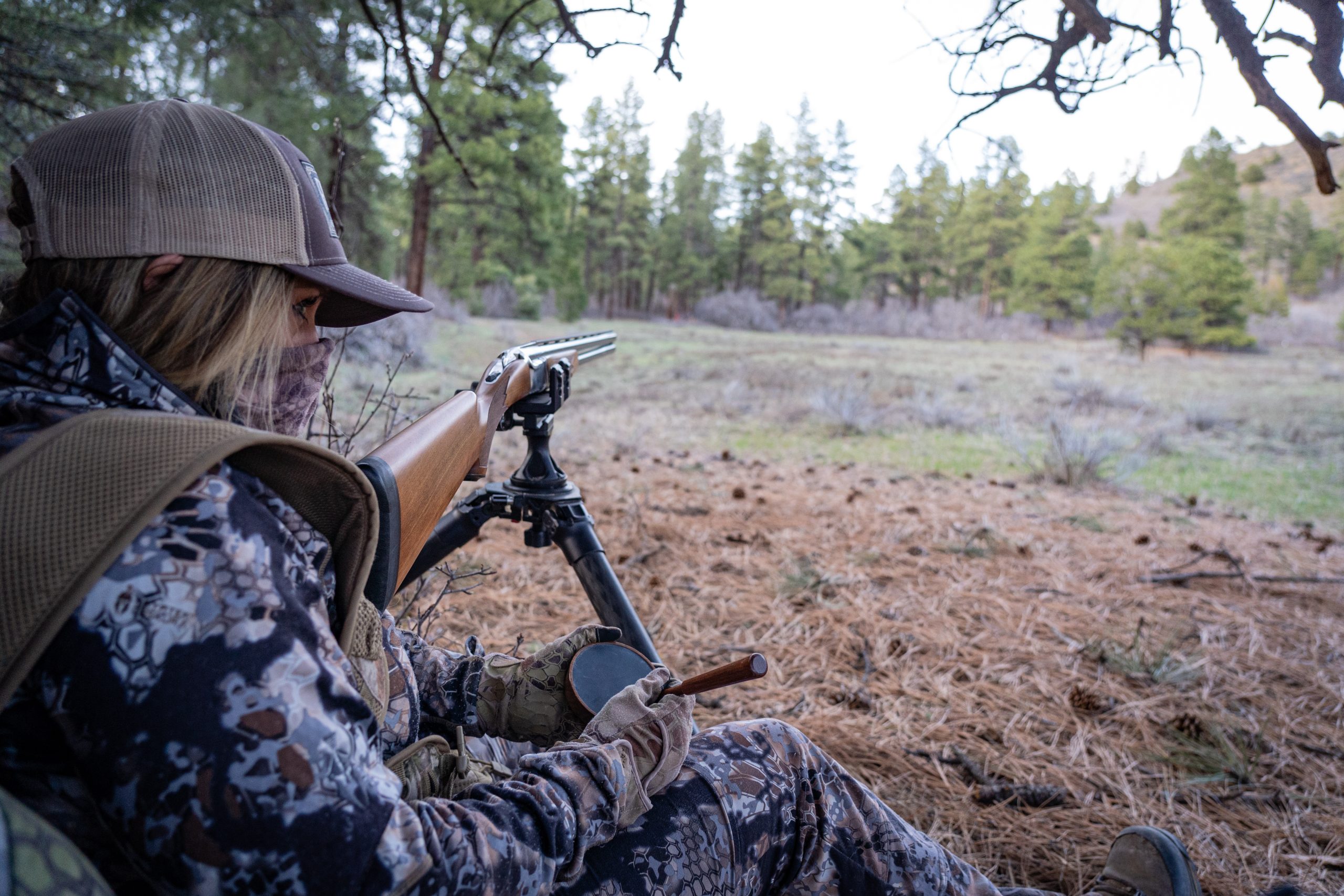 Woman sitting with shotgun on the ground