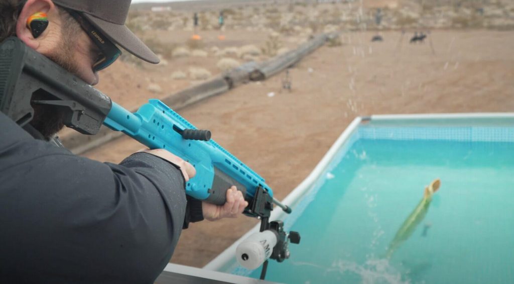 A man shoots an air rifle into a pool.