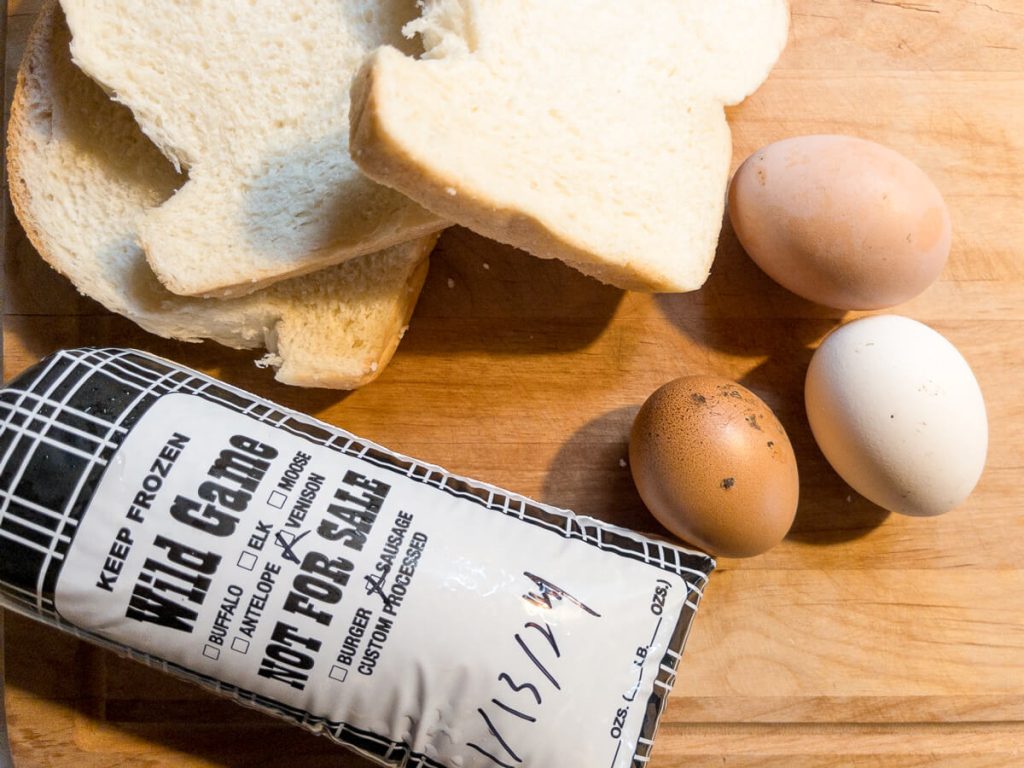 A wooden counter with venison sausage and eggs from homegrown chickens