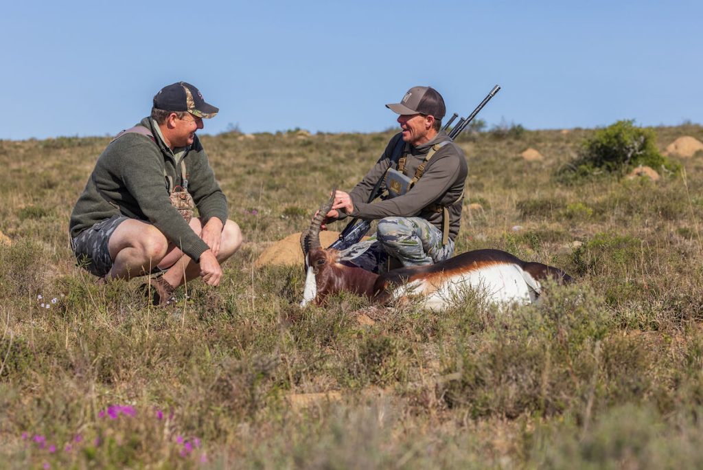 Two hunters in field with exotic animal