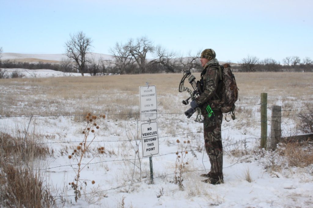 man bowhunting crossing fence perimeter on public land