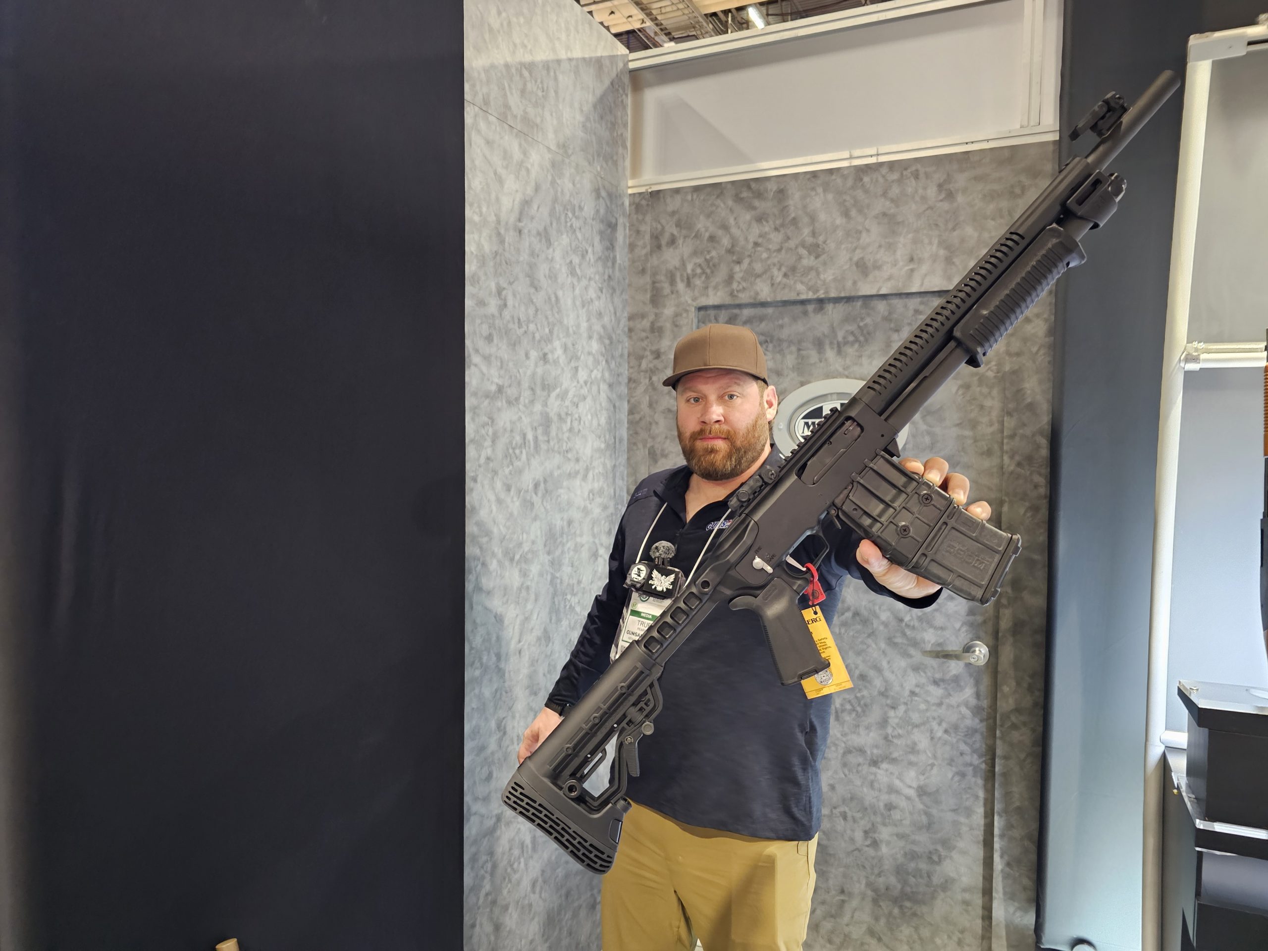 Holding the new Mossberg 590RM at SHOT Show 2025. A pump-action, magazine-fed shotgun is on display.